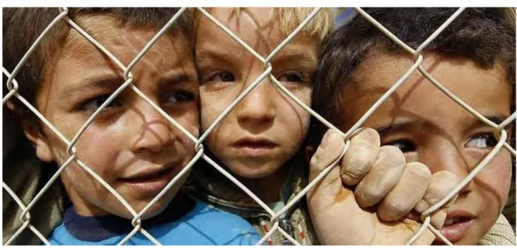 Figura 14: Niños sirios observan desde una valla del campo de refugiados de Magraf en Jordania 