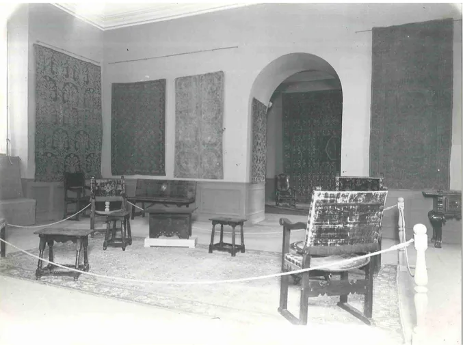 Fig. 2. Sala de la exposición de Alfombras antiguas españolas. Sobre la alfombra y a la izquierda de la fotografía  el sillón frailero CE01181 y a la derecha, parte de la mesa CE02702