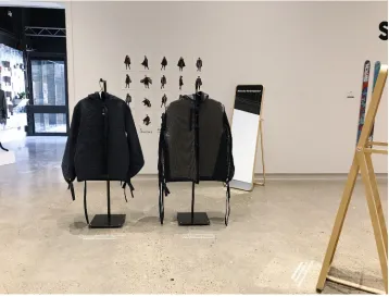 Figure 5The overall exhibition design with the two Gender Variant Jackets placed in the middle, with a photo display behind and two mirrors on the edge of the space.