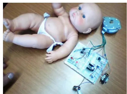 Figure 5: The doll with an artificial “tumor” (a stepper  motor, shown near the head of the doll) which is under the control of a PICAXE microcontroller (installed on the proto board)