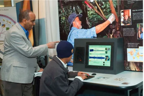 Fig. 1 Two visitors at thewhich includes an interactive screen and a background photo of the “Explore Evolution” exhibition fly unit,scientist working in the field