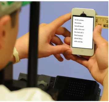 Figure 1. Reading on the Apple iPod Touch using the hands. The device is suspended from a stable mount in front of the participant, whileeye movements are observed using an eye tracking device (partially visible toward the bottom of the photo)