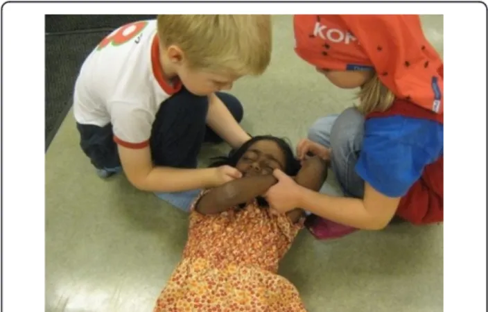 Figure 1 shows children practicing first aid during the course.