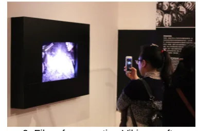 Figure 7. Audio-visual media spatially detached from object. A screen in a display case presenting a virtual 3D version of an object is being watched by a man in black, while a lady in red carrying a child is the only one actually looking at the original o