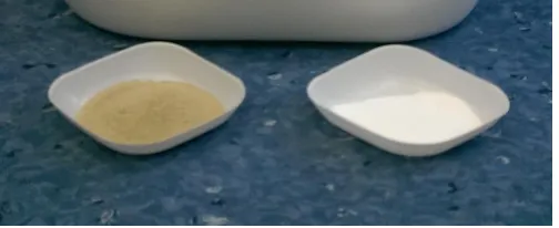 Figure 6 Photograph of the barrel containing a suspension of MIL-53(Al) formed by continuous flow in our scaled-up reaction (centre), together with a commercial sample (bottom left) and dried MIL-53(Al) from the barrel (bottom right)