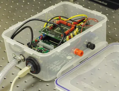 FIG. 3. A photo of the customized sensing box. Consisting of two ports for gas ﬂow, two wires for connection to an externalDC power supply and a USB connection, with the CMOS system sitting inside (Inset: Illustration of the experimental setup).