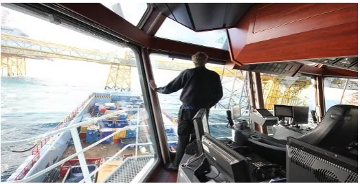 Figure 3. First officer looking outside to help the dynamic positioning operator position the vessel under the middle of the crane on the platform (Photo: Yushan Pan)