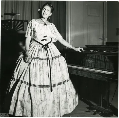 Figure 5.  The “Louisiana Lady” in her full costume standing aside the piano she would play during her lecture-recitals