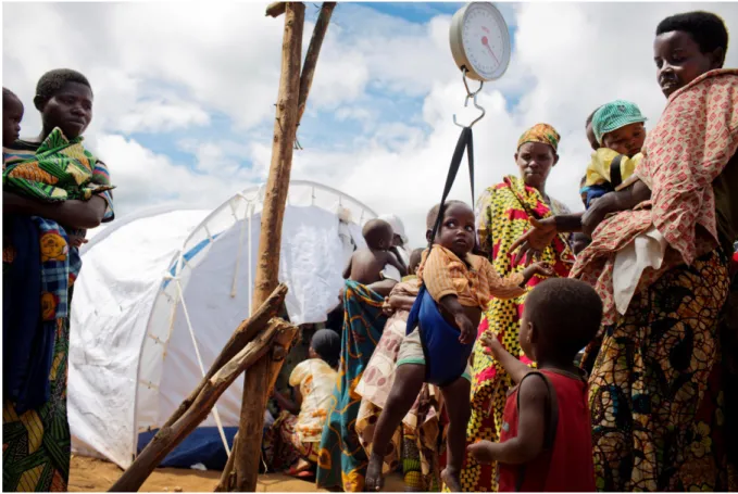 Figure 1: A mother weighs her baby at a nutritional screening centre for new arrivals in Mahama Refugee Camp,  Rwanda