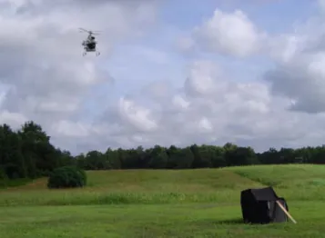 Fig. 13. Photograph of a vision-aided INS flight test, showing the  helicopter hovering in the upper left and the black optical target in the  lower right