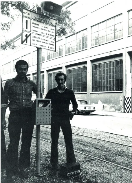 Fig. 7. Armando Puglisi (a sinistra) e Vincenzo Francone (a destra) posano accanto alla scultura Dall’alto di una palina del tram – apertura del processo a Stalin, (1972, ferro, legno, ghiaia, impianto audio) provvisoriamente installata in Corso Parco Regio, Torino 1972.