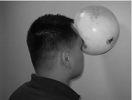Figure 1 Standing isometric neck exercises. The patient stands upright, slightly contracts his abdominal muscles for stability, and pushes his forehead against a ball that is held against a wall (isometric neck ﬂ exor contraction) for at least 10 seconds